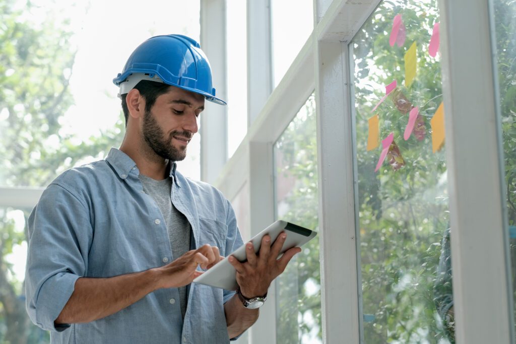 Engineer working in office with glass windows and using tablet to manage system