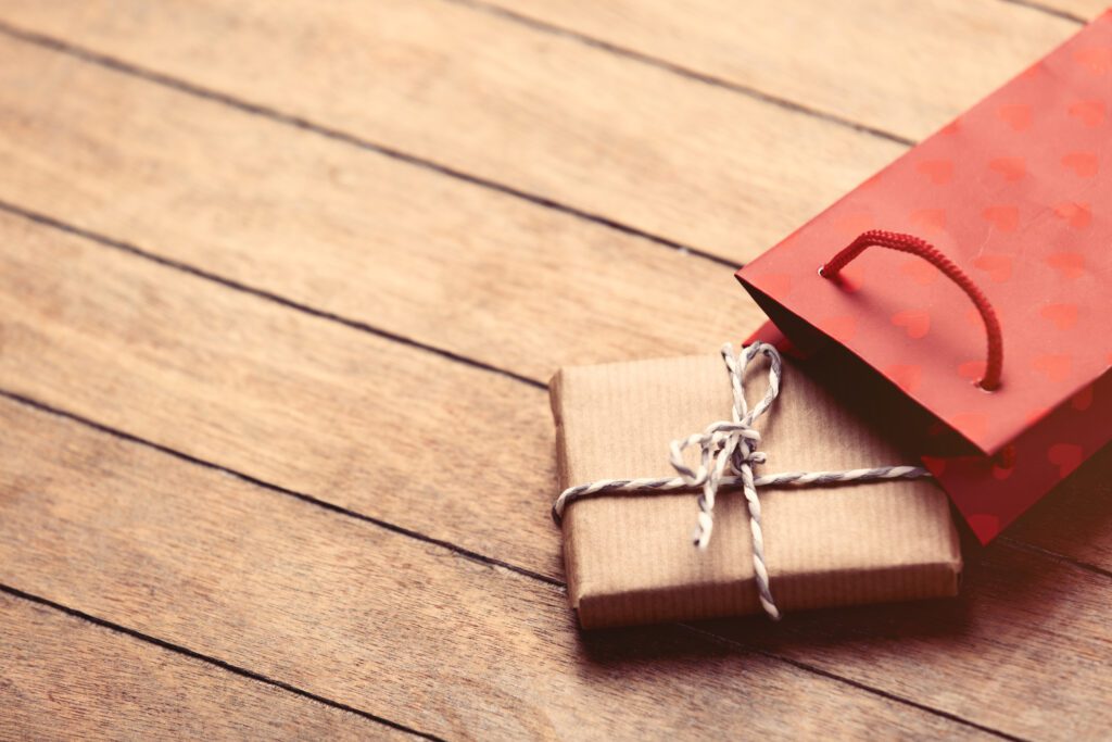 beautiful gift and red shopping bag lying on the wonderful brown wooden background