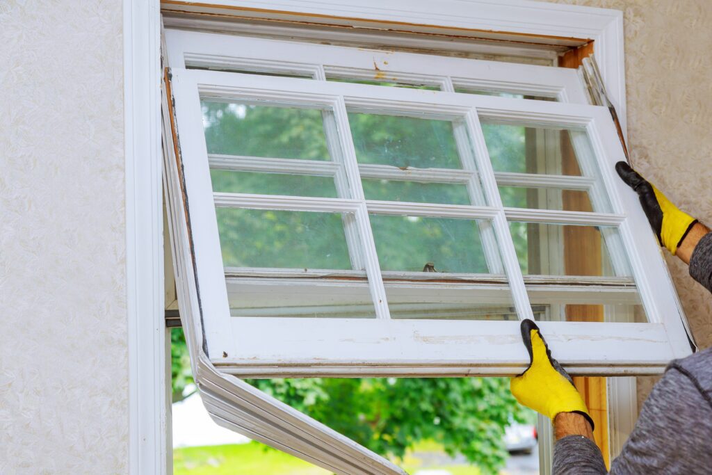 Worker's hands replacing the old wooden window